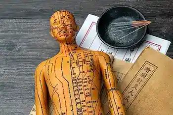 Auf dem Tisch liegen Akupunkturmodelle und medizinische Bücher. Akupunktur ist eine traditionelle chinesische medizinische Methode