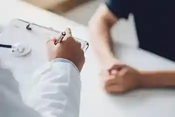 Arzt mit Testergebnissen und Patientenberatung am Schreibtisch,